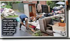  ?? ?? RECORD: A man washes his hands in the gutter while piling belongings on street