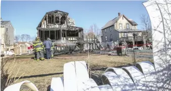  ?? NICOLAUS CZARNECKI / HERALD STAFF ?? SAVING THE DAY: Fire crews, seen through a melted fence, extinguish hot spots at the scene of a fire on First Street in Melrose on Sunday. The homeowners escaped unharmed thanks to the barking of their dog, Emmie.