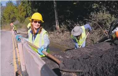  ?? DAN HONDA/STAFF PHOTOS ?? Karin Illes, of Los Gatos, gets a shovel full of cold asphalt material to fill a pothole on Highland Way in Los Gatos. The volunteer “Vigilante Pothole Team” taught themselves how to safely dump, shovel and smooth asphalt in the Santa Cruz Mountains.