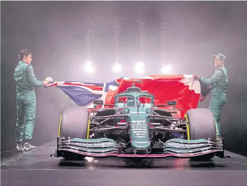  ?? AFP ?? Aston Martin drivers Sebastian Vettel, right, and Lance Stroll unveil the team’s new car for the 2021 season.