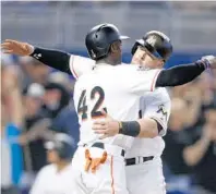  ?? MICHAEL REAVES/GETTY IMAGES ?? Justin Bour gets a hug from Cameron Maybin, left, after hitting a two-run home run in the seventh inning at Marlins Park. All players wore No. 42 in honor of Jackie Robinson Day.