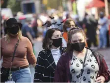  ??  ?? WARDING OFF ALL EVILS: Visitors wear masks, above and left, as they walk along the Essex Street Pedestrian Mall in Salem on Friday.