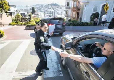  ?? Paul Kuroda / Special to The Chronicle ?? On Lombard Street, cadet Jessica Banuelos passes out flyers to alert drivers to take valuables with them.