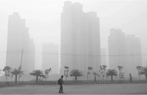  ?? — Reuters photo ?? A man walks through smog near Delhi, India.