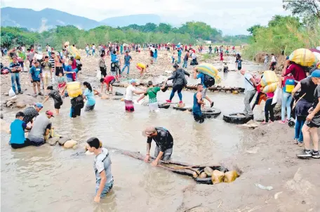  ??  ?? Imagen de archivo de venezolano­s cruzando la frontera con Colombia. A través de ríos, montes y el mar, los venezolano­s huyen de la crisis humanitari­a que sufre su país, que ha causado la emigración de alrededor de 3 millones y medio de personas.