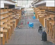  ??  ?? Constructi­on workers fold a tarp sheet at a closed building complex being built as part of the athletes’ village to be used during the postponed Olympic and Paralympic Games in Tokyo. (AP/Hiro Komae)