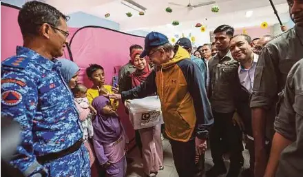  ?? (Foto Ghazali Kori/bh) ?? Anwar diiringi Ahmad Samsuri menyantuni mangsa di PPS SK Telaga Papan di Setiu, semalam.