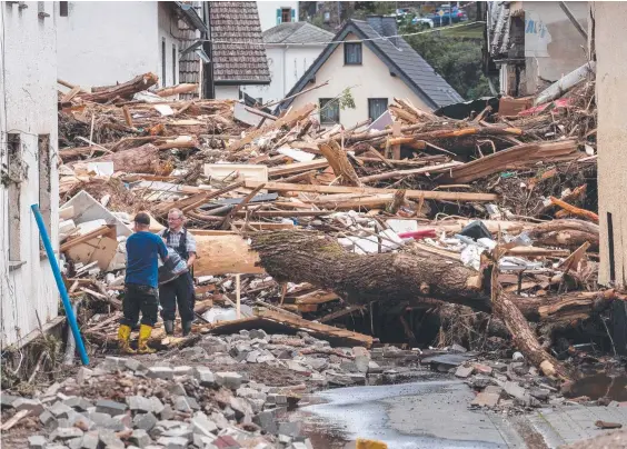  ??  ?? Two men recover items from the debris of houses destroyed by the floods in Schuld near Bad Neuenahr, Germany. Picture: AFP