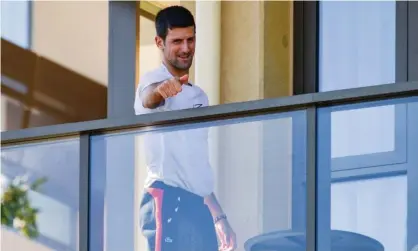  ?? Photograph: Brenton Edwards/AFP/Getty Images ?? Novak Djokovic gestures on Monday from his hotel balcony in Adelaide, where he is in quarantine before the Australian Open.