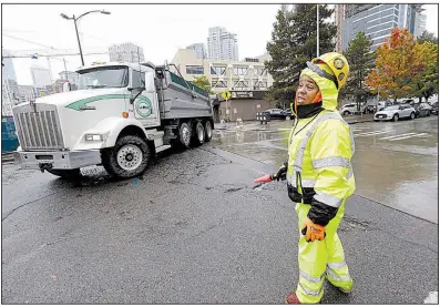  ?? AP/ELAINE THOMPSON ?? A constructi­on worker directs traffic around a constructi­on site near Amazon’s headquarte­rs on Tuesday in Seattle. Today is the deadline for cities to submit bids for Amazon’s second headquarte­rs developmen­t.