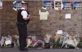  ?? The Associated Press ?? A police officer stands near floral tributes in Finsbury Park after an incident where a van struck pedestrian­s, in London on Monday. British authoritie­s and Islamic leaders moved swiftly to ease concerns in the Muslim community after a man plowed his...