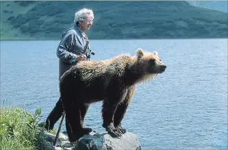  ?? MAUREEN ENNS STUDIO LTD. NYT ?? Charlie Russell stands with a young grizzly at a lake on Russia’s Kamchatka Peninsula in this undated photo.