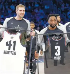  ?? AP PHOTO/CHUCK BURTON ?? Team Giannis’ Dirk Nowitzki of the Dallas Mavericks, left, and Team LeBron’s Dwyane Wade of the Miami Heat are given jerseys during the second half of the NBA All-Star game Sunday in Charlotte, N.C.