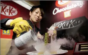  ?? Bloomberg News/TOMOHIRO OHSUMI ?? An employee pours liquid nitrogen into a bowl while serving a frozen KitKat dessert during a media preview of the KitKat Chocolator­y Ginza store, operated by Nestle SA, in Tokyo, Japan. The Swiss firm is reportedly paying $500 million for a majority...