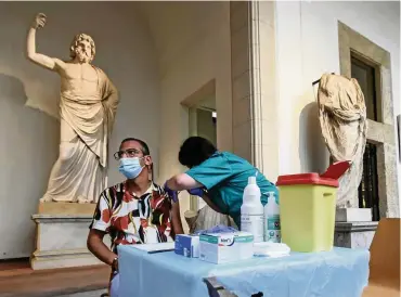  ?? FOTO: PICTURE ALLIANCE / NURPHOTO ?? Zwischen Statur und Sarkophag: In Palermo lassen sich die Bewohner im Museum impfen – und bekommen zur Belohnung freien Eintritt.