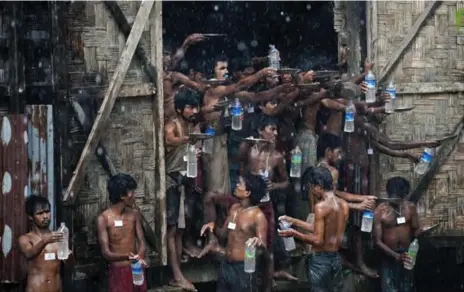  ?? YE AUNG THU PHOTOS/AFP/GETTY IMAGES ?? Migrants, who were found at sea, collect rain water at a temporary shelter outside Maungdaw, Burma, on Thursday.