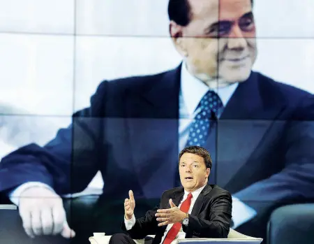  ??  ?? Il segretario del Pd, Matteo Renzi, negli studi di «Porta a Porta» su RaiUno, alle sue spalle un’immagine di Silvio Berlusconi, leader di Forza Italia