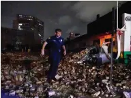  ??  ?? A New Orleans police officer looks over the debris of a building that collapsed during Hurricane Ida in New Orleans