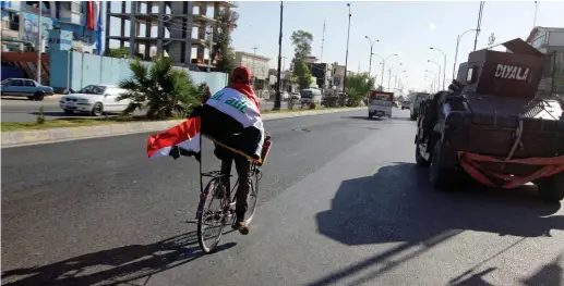  ??  ?? A MAN wearing an Iraqi flag rides a bicycle in Kirkuk earlier this year.