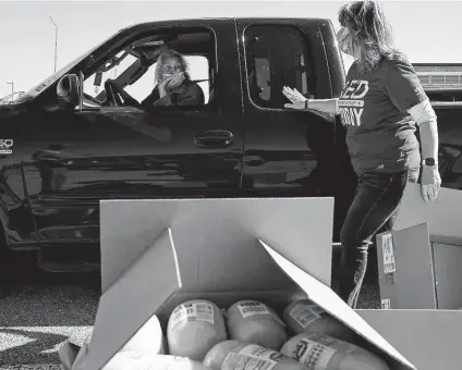  ?? Photos by Lisa Krantz / Staff photograph­er ?? Ernestina Hernandez picks up groceries Friday with the help of volunteer Linda Eaton during the San Antonio Food Bank’s mega distributi­on at Gustafson Stadium. Hernandez got extra bread to make sandwiches for the homeless in her community.