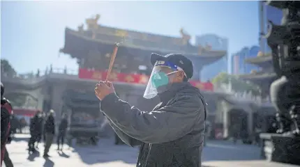  ?? REUTERS ?? A man wearing a protective mask and face shield worships at the Buddhist Jing’an Temple in Shanghai, China on Friday.