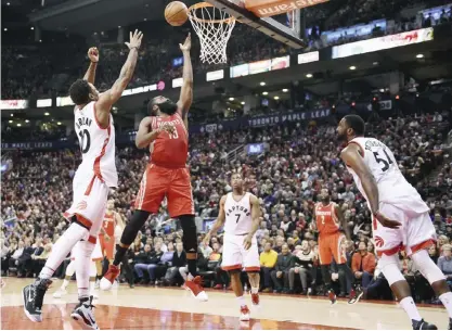  ?? —AP ?? TORONTO: Houston Rockets guard James Harden (13) scores as Toronto Raptors guard DeMar DeRozan (10) defends and guard Kyle Lowry (7) and forward Patrick Patterson (54) look on during the second half of an NBA basketball game in Toronto on Sunday.