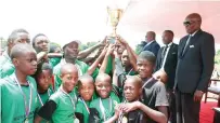  ?? ?? Boys lift their trophy after a soccer match which was organised by First Lady Dr Auxillia Mnangagwa at the skills developmen­t centre in Mbare yesterday. Looking on are Minister of State and Devolution for Harare Metropolit­an Charles Tawengwa and Harare Mayor Clr Jacob Mafume