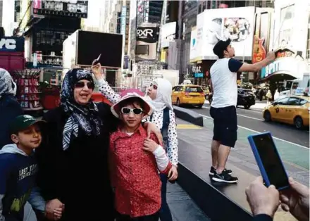  ?? NYT PIC ?? Rihab Taki with her son, Ibrahim, and niece, Hayat, in Times Square. Her son, Ghaizwan (right), is using a selfie stick. The family is adapting to new life in the United States.