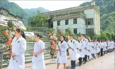  ?? XUE SHENGYU / FOR CHINA DAILY ?? Medical workers pay tribute to people who died in the May 12, 2008 Wenchuan earthquake at a memorial site in Sichuan province on Friday. More than 69,000 people were killed in the disaster.