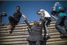  ??  ?? Migrants rushing to climb over a border fence