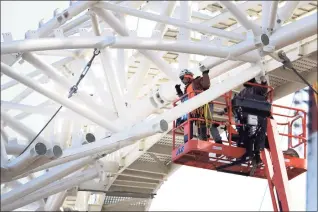  ?? Ned Gerard / Hearst Connecticu­t Media ?? Workers guide a section of metal framing into place above the Harbor Yard Amphitheat­er currently under constructi­on in Bridgeport on Jan. 25. The framework will support the massive fabric tent roof that will soon cover the amphitheat­er.