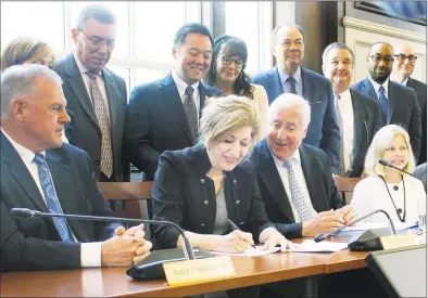  ?? Pat Eaton-Robb / Associated Press file photo ?? University of Connecticu­t President Susan Herbst, seated center, signs a contract on June 26, 2019, on the school’s campus in Storrs to move most of the schools athletic teams from the American Athletic Conference to the Big East.