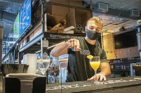  ?? Sydney Herdle photos/Special to the Post-Gazette ?? Champs Downtown bartender Jordan Gitzen, a fifth-year nuclear engineerin­g major at Penn State, makes a drink Sunday at the bar in State College.