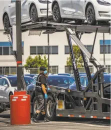  ??  ?? A man loads cars at the factory, reopened in defiance of county rules prohibitin­g car manufactur­ing during shelter in place.
