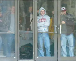  ?? MATT GENTRY/THE ROANOKE TIMES ?? Virginia Tech students watch from the doorway of McBryde Hall on the Virginia Tech campus in Blacksburg as police infiltrate the area where a shooting took place on April 16, 2007. A gunman opened fire in a Virginia Tech dorm and then, two hours later, in a classroom across campus, killing 32 people.