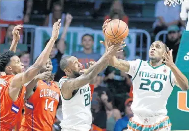  ?? AL DIAZ/MIAMI HERALD ?? Miami forwards Kamari Murphy (21) and Dewan Huell (20) chase a rebound against Clemson as the team notched another quality conference win at home on Saturday.