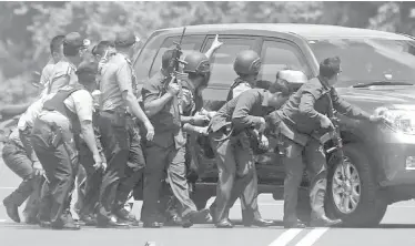  ??  ?? Police officers take cover behind a vehicle during a gun battle with attackers near the Starbucks café hit by a suicide bomber Thursday in Jakarta, Indonesia.