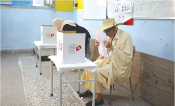  ?? (Muhammad Hamed/Reuters) ?? A MAN READS his ballot paper at a polling station during the presidenti­al election in Tunis yesterday.