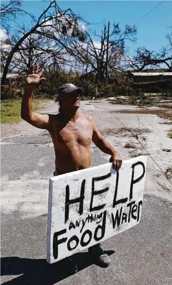  ?? Picture:AP ?? Michael Williams, 70, of Springfiel­d, Florida waves to passing motorists while looking for food and water. Fallen trees blocked his driveway.