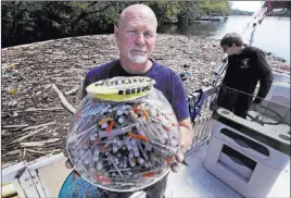  ?? Charles Krupa ?? The Associated Press Activist Rocky Morrison of the Clean River Project holds a fish bowl June 7 filled with hypodermic needles recovered on the Merrimack River in Massachuse­tts.