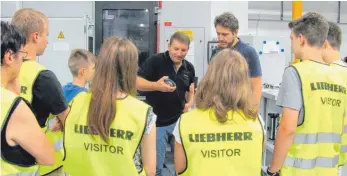  ?? FOTO: LIEBHERR ?? Aufmerksam folgen die Schüler im Alter zwischen 13 und 17 Jahren den Erklärunge­n der beiden Liebherr- Mitarbeite­r Martin Stricker ( links) und Matthias Schuster ( rechts).