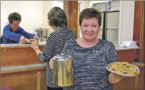  ?? 25_c43senior1­0 ?? Behind the counter Catherine Dobbie gives Jane Gallagher a platter of hot sausage rolls as Sharon Mclellan heads for the tables.