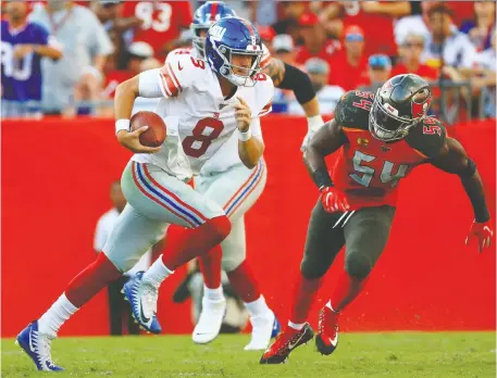  ?? MIKE EHRMANN/GETTY IMAGES ?? Rookie New York Giants quarterbac­k Daniel Jones, left, scrambles while under pressure from the defence Sunday during a game against the Buccaneers in Tampa, Fla., where the No. 6 overall pick led his team to an 18-point comeback in his NFL debut as a starter.