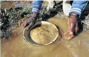  ??  ?? RICHES: An illegal mineworker pans for gold flakes. Workers can earn around R100 000 in three months