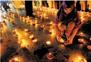  ?? Asif Hassan / AFP / Getty Images ?? A supporter of cleric Tahir-ul-Qadri lights a candle in Karachi, Pakistan, to remember violence victims.