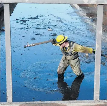  ?? Michael Owen Baker For The Times ?? A SAN LUIS OBISPO firefighte­r pulls a hose to clear a drain in a flooded parking area at a housing complex in Montecito, Calif., in January. A new storm poses a fresh threat to the community this week.