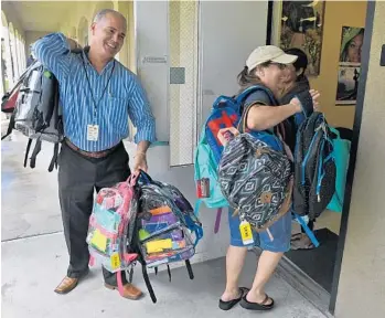  ?? JIM RASSOL/STAFF PHOTOGRAPH­ER ?? Kerri Kaiser of Christ Fellowship and Ricardo Pino of the The School District of Palm Beach County unload donated backpacks and school supplies for students relocated from recent hurricane-damaged areas.