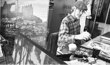  ??  ?? Artist Mulfinger works on a watercolou­r of a West End scene in his studio at Art Crossing in Greenville, South Carolina.