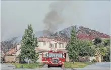  ?? IRFAN KHAN TNS ?? A fire engine is stationed at a Lake Elsinore, Calif. home as Holy Fire, which has spread across 9,614 acres as of Thursday, burns behind.