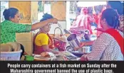  ??  ?? People carry containers at a fish market on Sunday after the Maharashtr­a government banned the use of plastic bags.